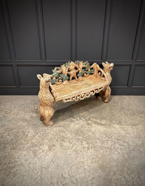 fig 1. A carved wooden two-seat bench featuring two rearing bears forming the sides and armrests, with scroll motifs and carved green foliage across the backrest.