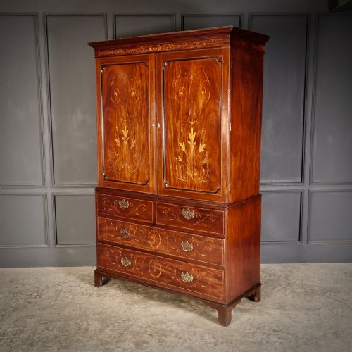 fig 1. An antique Georgian mahogany gentlemans wardrobe with detailed marquetry inlay on the double doors and lower drawers, standing on bracket feet.