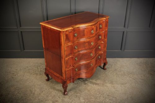 fig 1. An antique walnut chest of drawers featuring a serpentine curved front, four graduated drawers with brass handles, and carved cabriole legs.