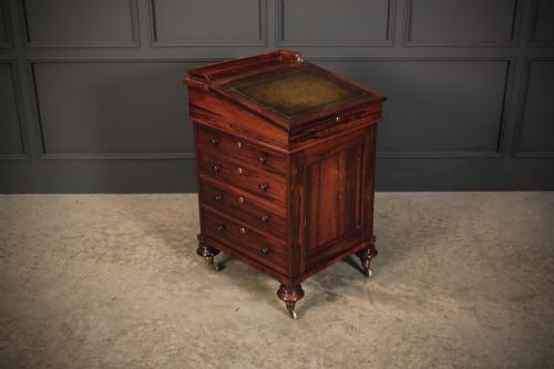 fig 1. A William IV rosewood Davenport desk featuring a sloped leather writing surface, side drawers with turned knobs, and turned feet on castors.