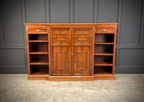 fig 2. An antique Edwardian walnut breakfront bookcase with a central section featuring geometric panelled doors flanked by open adjustable shelving.