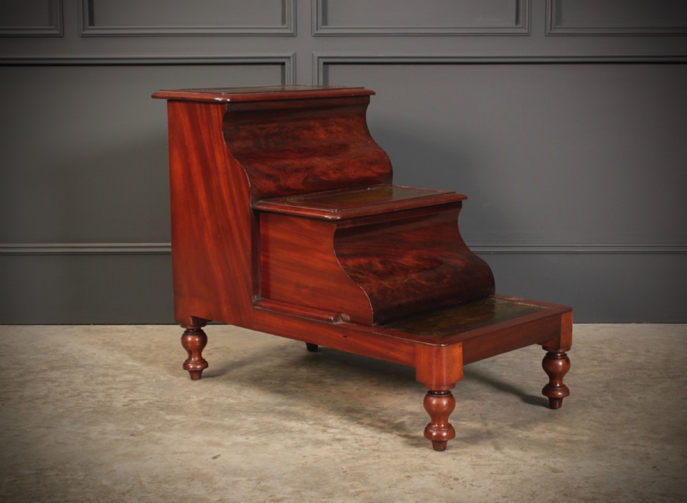 A three-tier Victorian mahogany library step unit featuring leather-lined treads and turned wooden feet.
