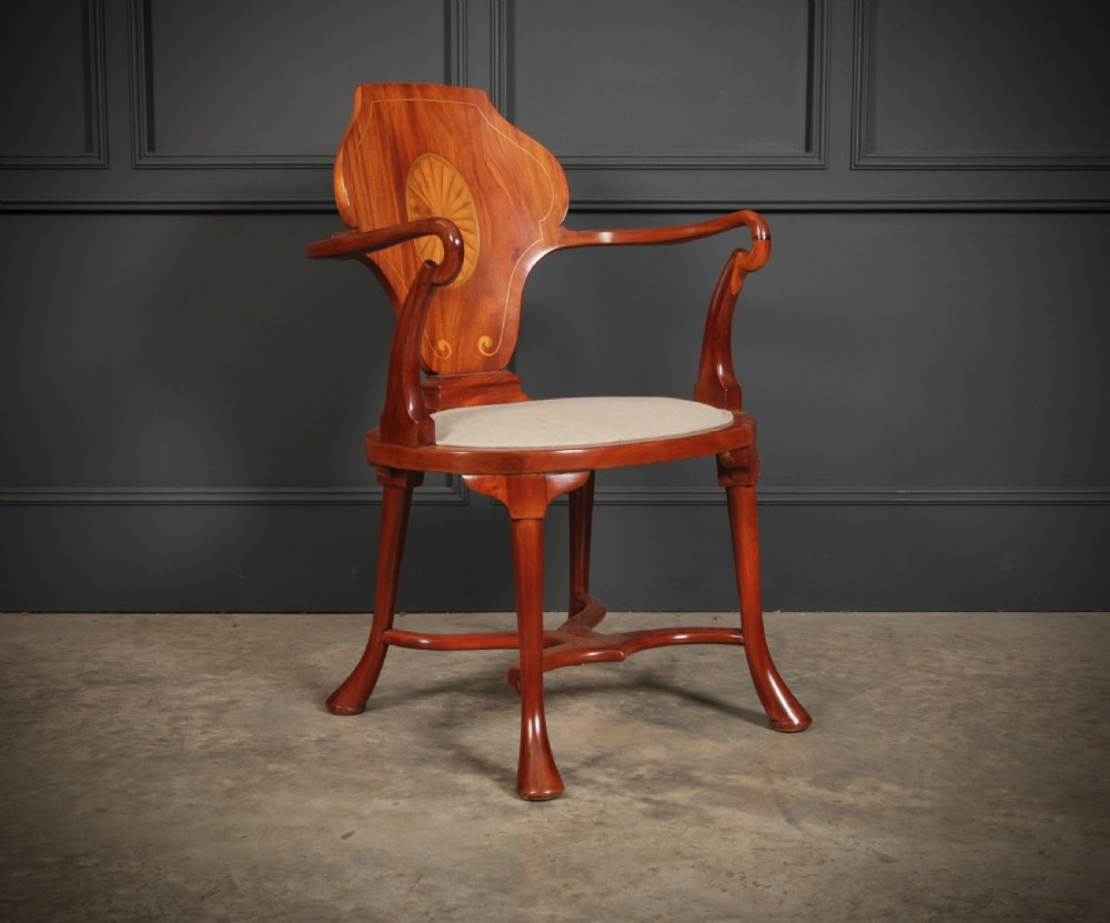 An Edwardian mahogany armchair with a decorative oval marquetry inlay on the back splat, swept arms, a cream upholstered seat, and an X-form stretcher. View II
