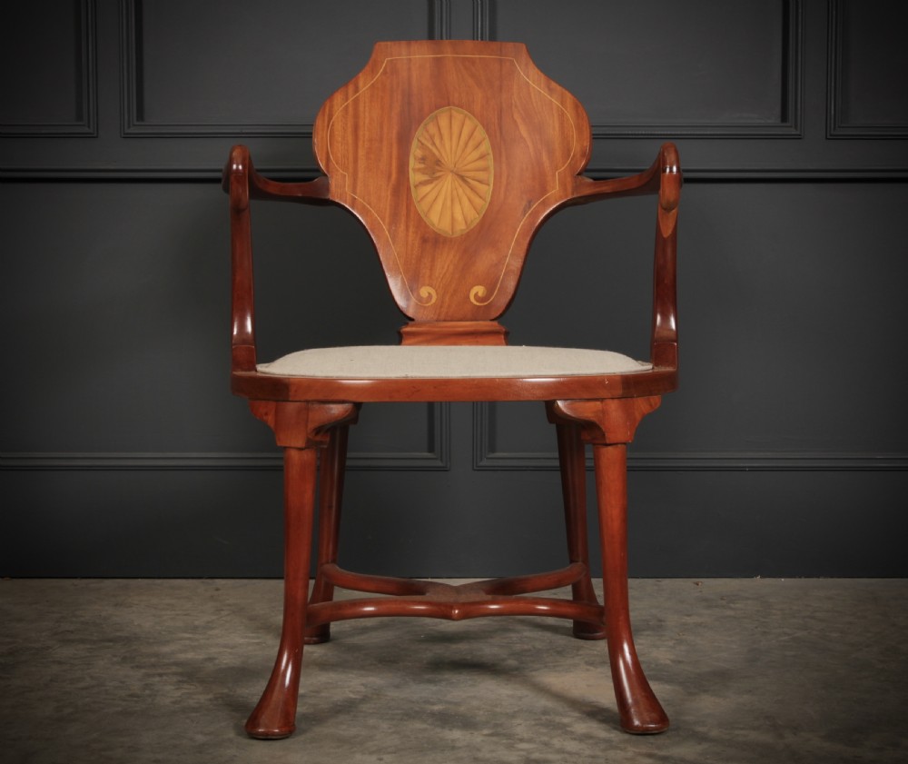 An Edwardian mahogany armchair with a decorative oval marquetry inlay on the back splat, swept arms, a cream upholstered seat, and an X-form stretcher. View VI