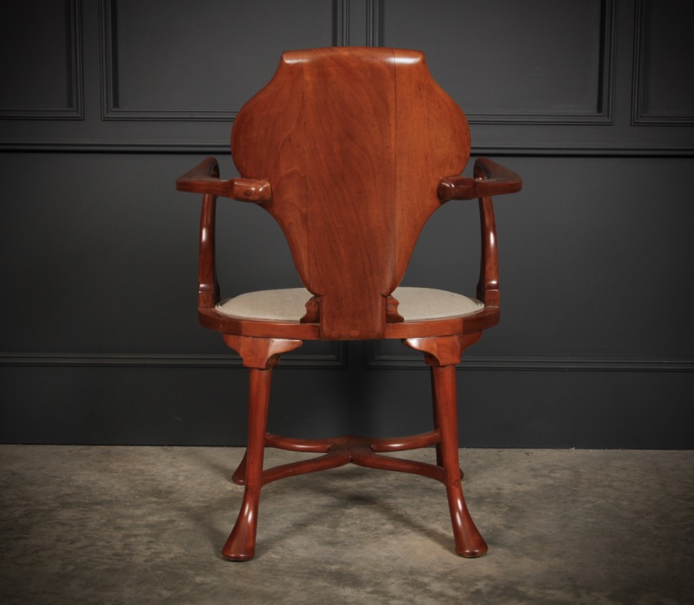 An Edwardian mahogany armchair with a decorative oval marquetry inlay on the back splat, swept arms, a cream upholstered seat, and an X-form stretcher. View IX