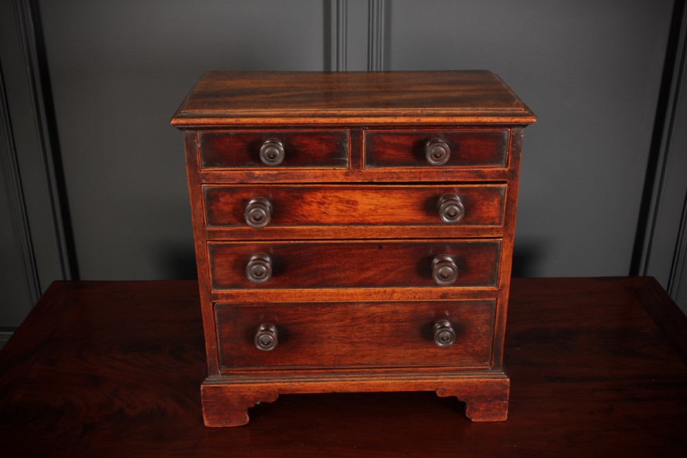 A Georgian style miniature mahogany chest of drawers with two short drawers over three long graduated drawers, turned knobs, and bracket feet. View IV