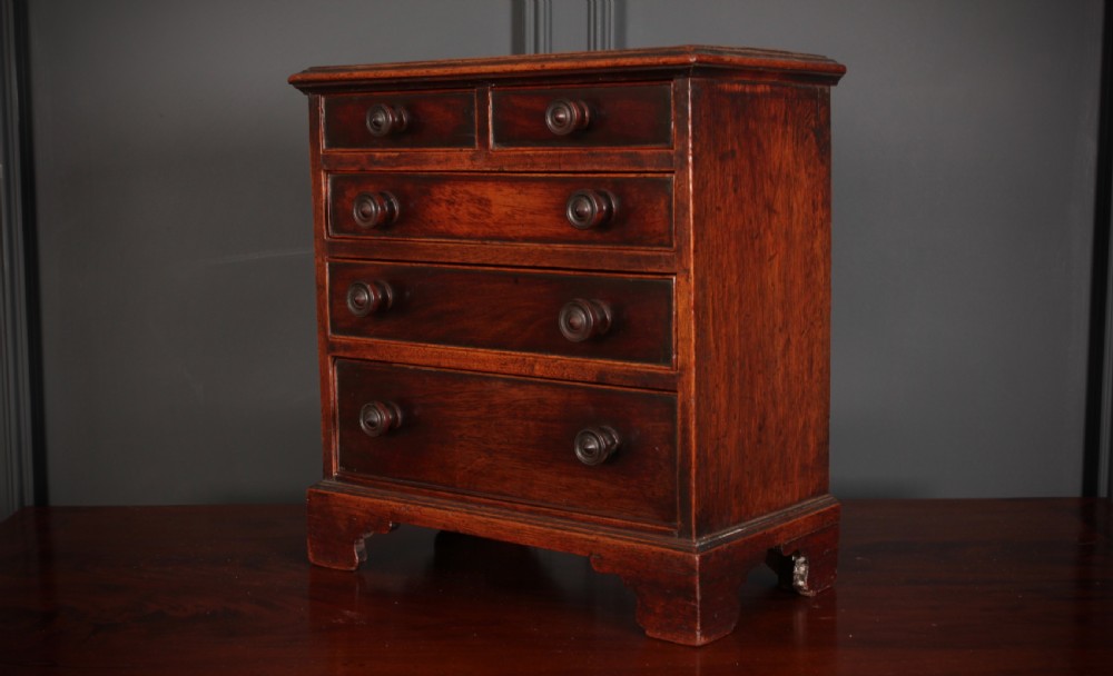 A Georgian style miniature mahogany chest of drawers with two short drawers over three long graduated drawers, turned knobs, and bracket feet. View VI