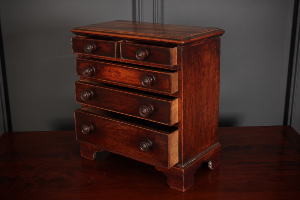 A Georgian style miniature mahogany chest of drawers with two short drawers over three long graduated drawers, turned knobs, and bracket feet. View VII