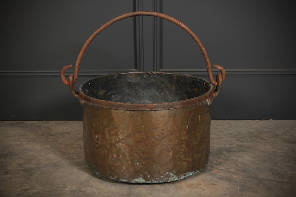 A large, hand-hammered Victorian brass cauldron featuring an iron rim collar and a heavy wrought iron swing handle. View III