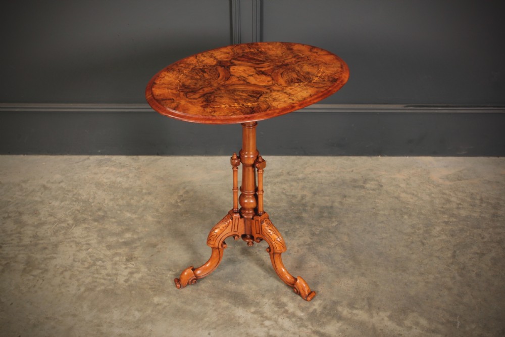 A Victorian oval occasional wine table made from figured walnut featuring floral marquetry inlay and a carved tripod base. View II