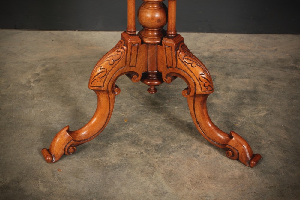 A Victorian oval occasional wine table made from figured walnut featuring floral marquetry inlay and a carved tripod base. View VIII