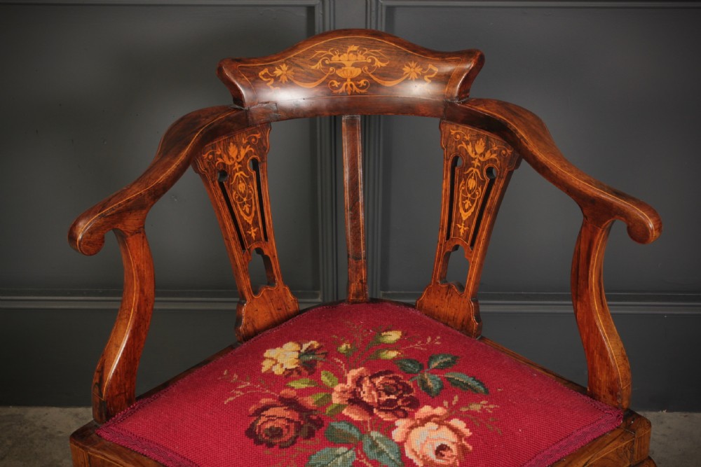 An antique rosewood corner chair featuring floral marquetry inlays on the curved top rail and splats, supported by cabriole legs and upholstered in red floral needlepoint. View II