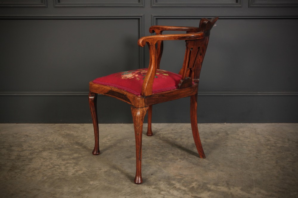 An antique rosewood corner chair featuring floral marquetry inlays on the curved top rail and splats, supported by cabriole legs and upholstered in red floral needlepoint. View X