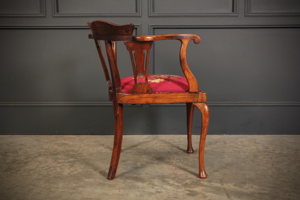 An antique rosewood corner chair featuring floral marquetry inlays on the curved top rail and splats, supported by cabriole legs and upholstered in red floral needlepoint. View XII