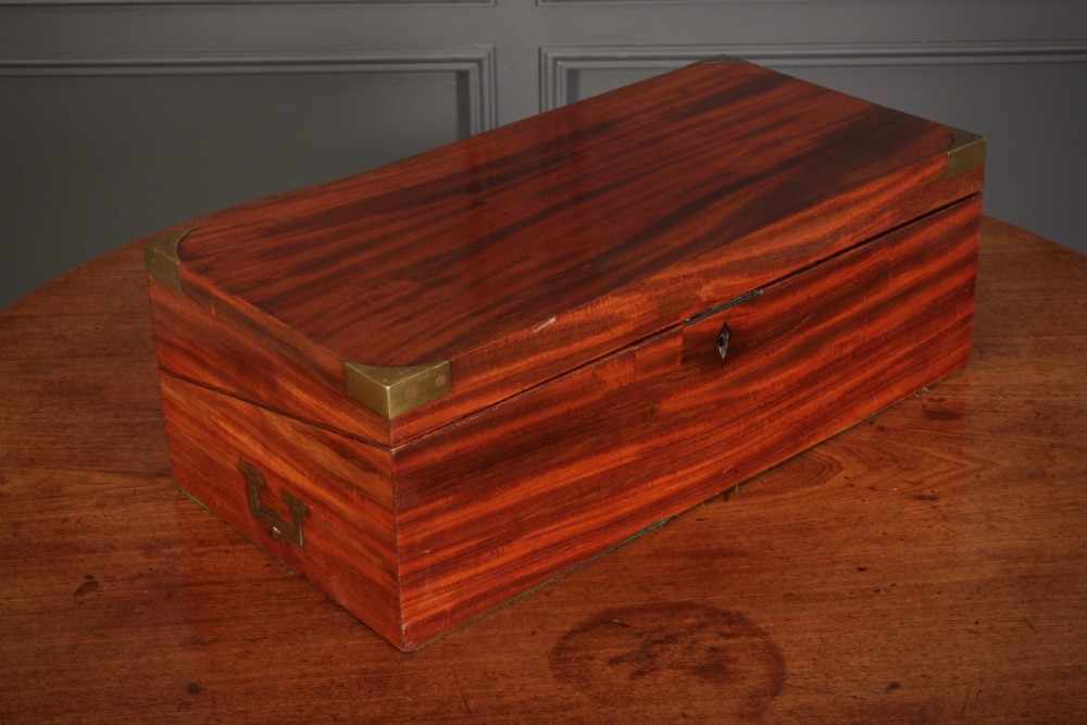 A closed rectangular Victorian mahogany writing slope with brass corner mounts and side carrying handles on a polished wooden surface.