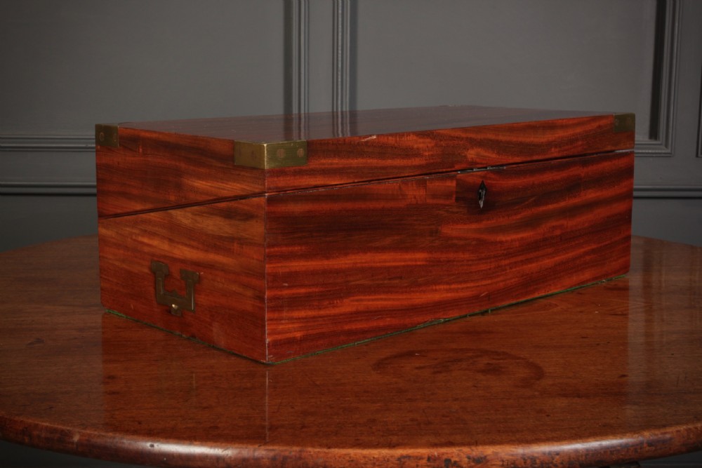 A closed rectangular Victorian mahogany writing slope with brass corner mounts and side carrying handles on a polished wooden surface. View II