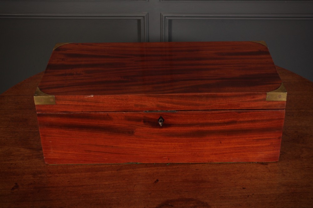 A closed rectangular Victorian mahogany writing slope with brass corner mounts and side carrying handles on a polished wooden surface. View IV
