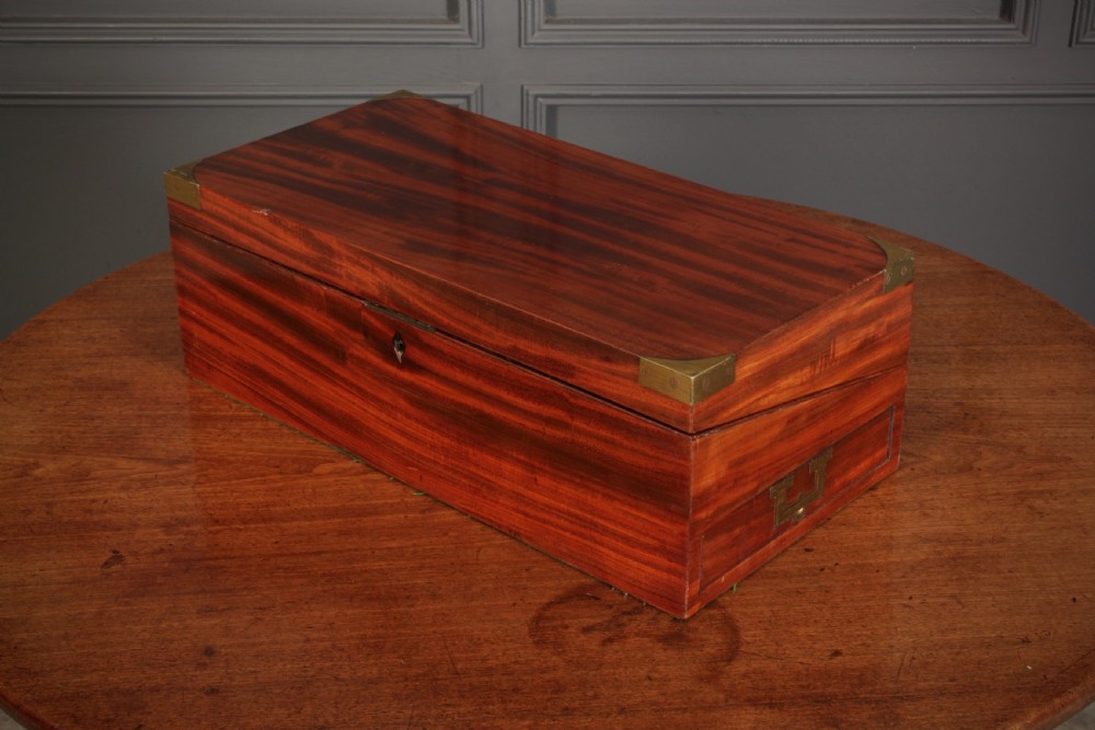 A closed rectangular Victorian mahogany writing slope with brass corner mounts and side carrying handles on a polished wooden surface. View V