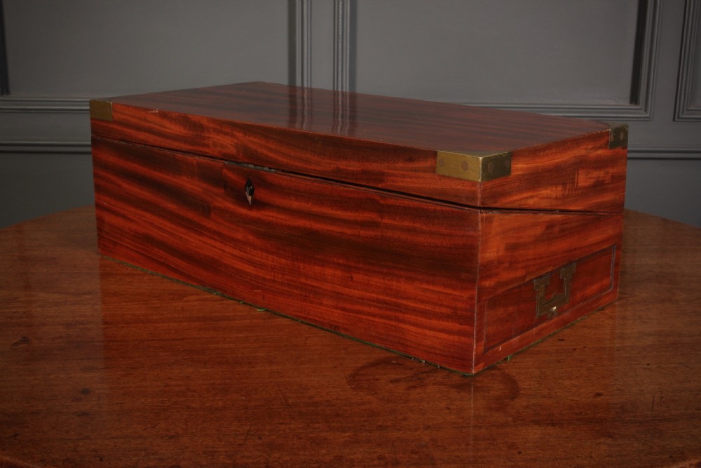 A closed rectangular Victorian mahogany writing slope with brass corner mounts and side carrying handles on a polished wooden surface. View VI