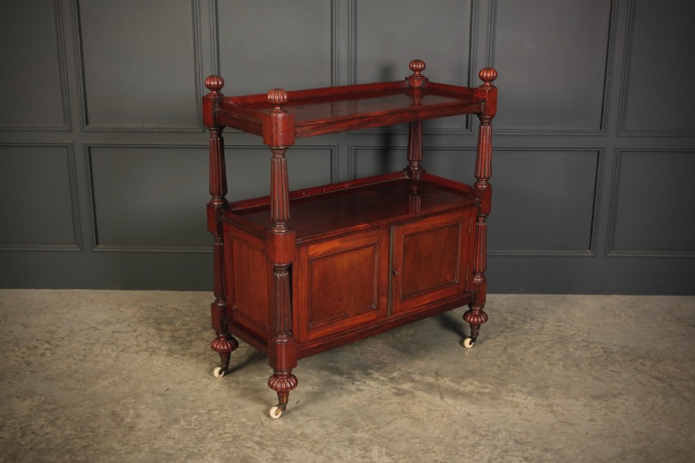 A Victorian mahogany two-tier buffet cabinet featuring turned reeded columns, a lower panelled cupboard, finials, and white castors.