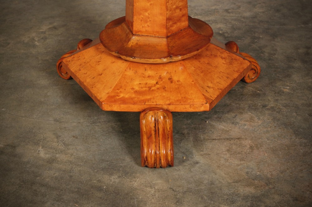 An Art Deco birds eye maple music stool featuring a round cream upholstered swivel seat with brass stud trimming above a faceted pedestal and octagonal base. View III