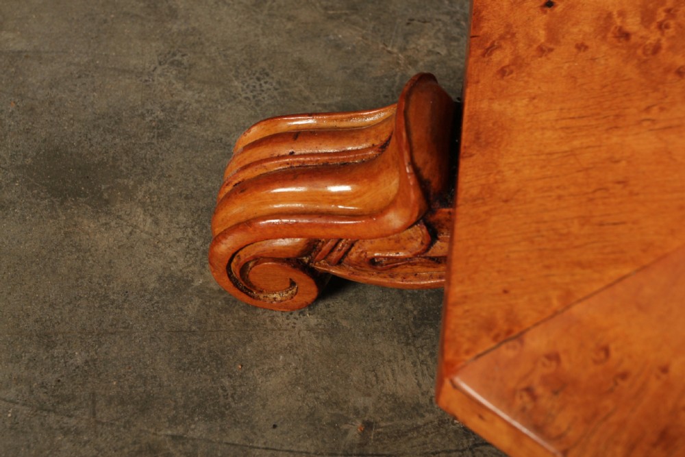 An Art Deco birds eye maple music stool featuring a round cream upholstered swivel seat with brass stud trimming above a faceted pedestal and octagonal base. View VIII