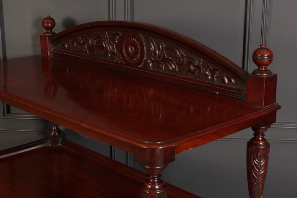 A Victorian mahogany three-tier buffet featuring carved turned column supports, a scrolled decorative backboard, and brass castors. View VI