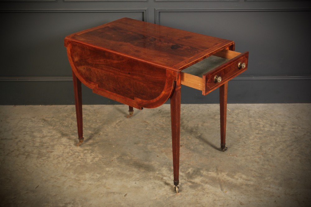 A Georgian mahogany Pembroke table featuring two drop leaves, subtle line inlay, a single front drawer with round brass handles, and tapered square legs on brass castors. View III