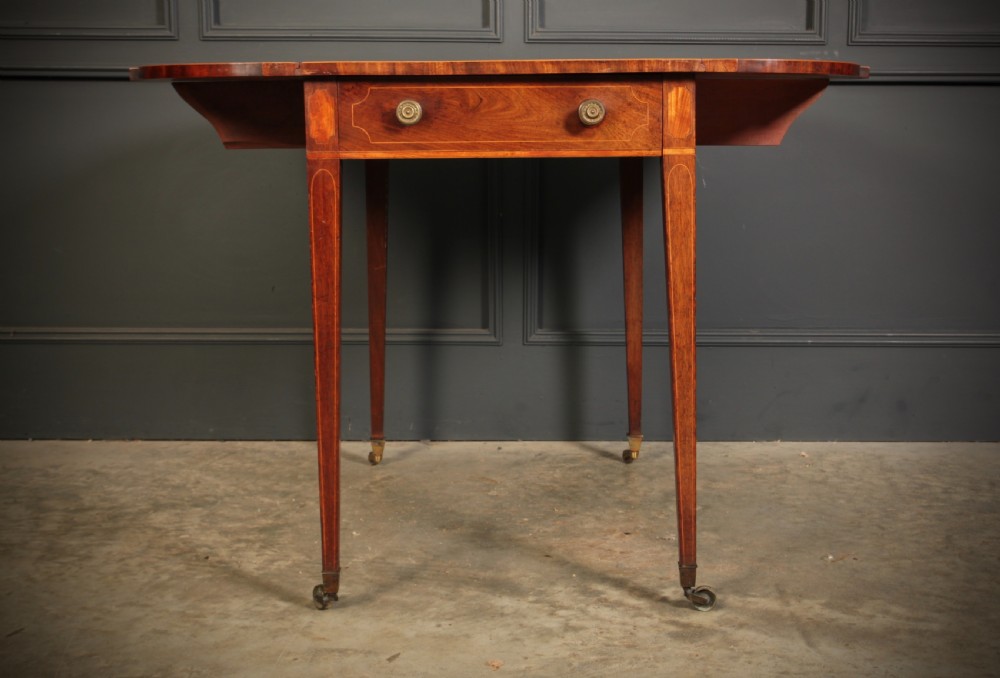A Georgian mahogany Pembroke table featuring two drop leaves, subtle line inlay, a single front drawer with round brass handles, and tapered square legs on brass castors. View VIII