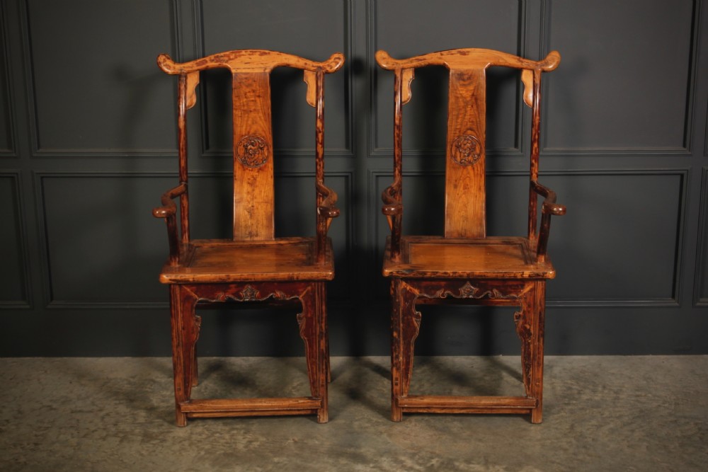 A pair of antique Chinese elm wood armchairs featuring curved yoke-back top rails, carved central back splats, and a warm honey-brown finish. View III