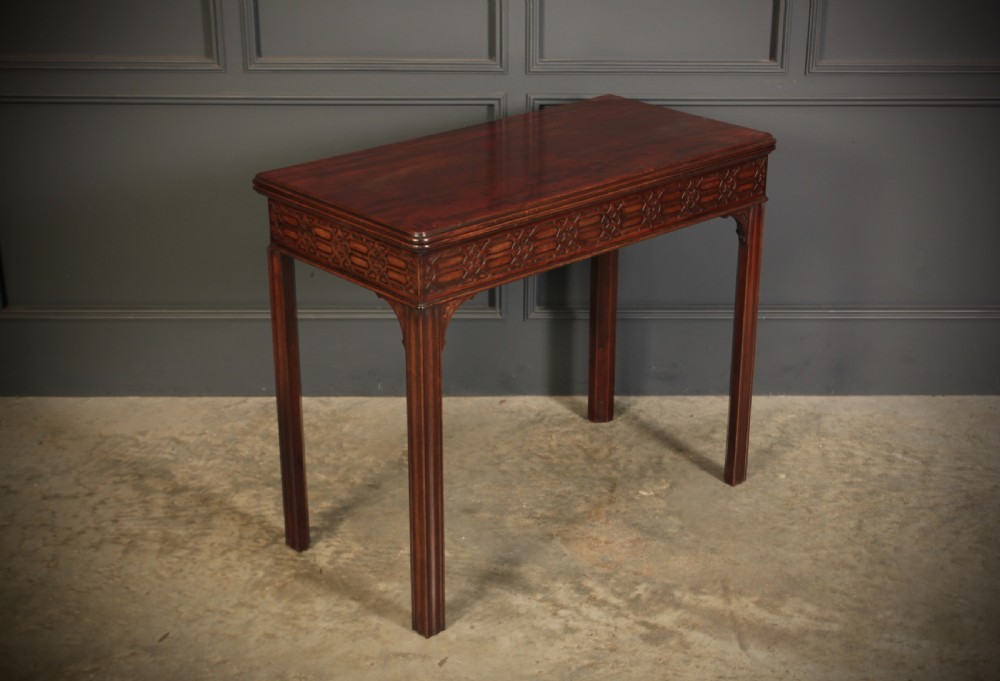 A dark mahogany fold-over card table in the Chinese Chippendale style featuring blind fretwork carved along the frieze and fluted square legs. View II