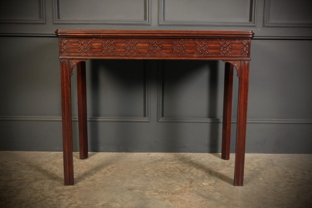 A dark mahogany fold-over card table in the Chinese Chippendale style featuring blind fretwork carved along the frieze and fluted square legs. View V
