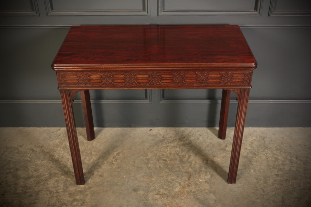 A dark mahogany fold-over card table in the Chinese Chippendale style featuring blind fretwork carved along the frieze and fluted square legs. View VI