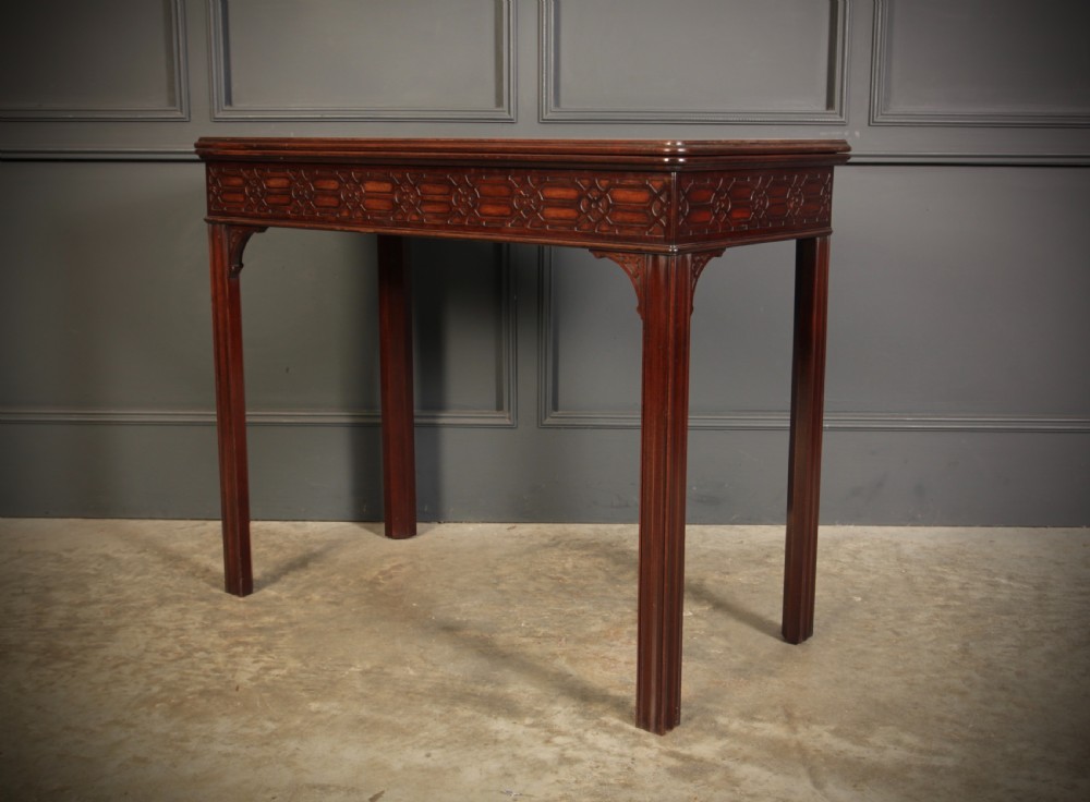 A dark mahogany fold-over card table in the Chinese Chippendale style featuring blind fretwork carved along the frieze and fluted square legs. View VIII