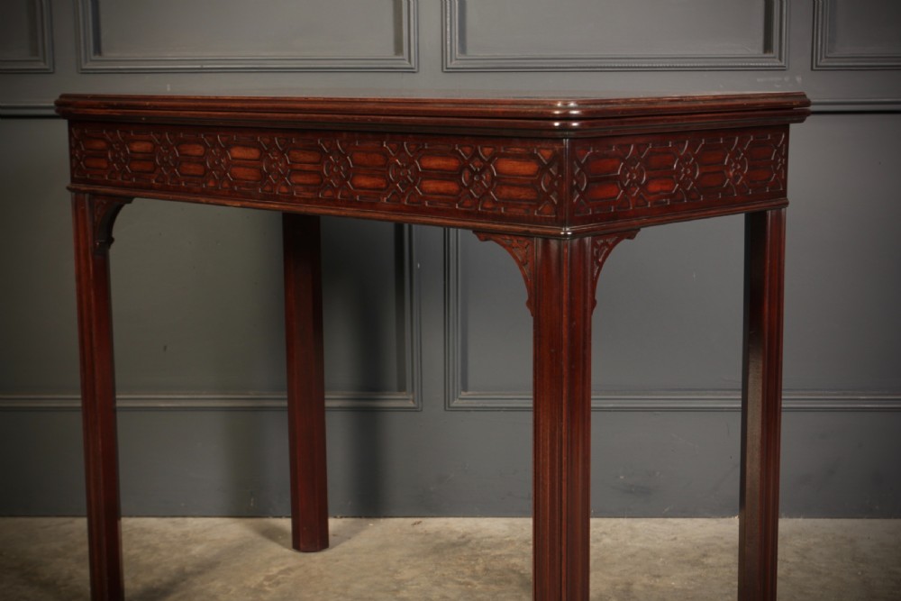 A dark mahogany fold-over card table in the Chinese Chippendale style featuring blind fretwork carved along the frieze and fluted square legs. View IX