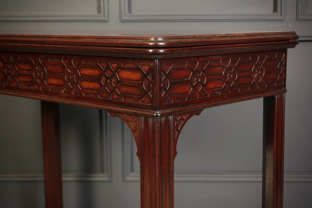 A dark mahogany fold-over card table in the Chinese Chippendale style featuring blind fretwork carved along the frieze and fluted square legs. View X