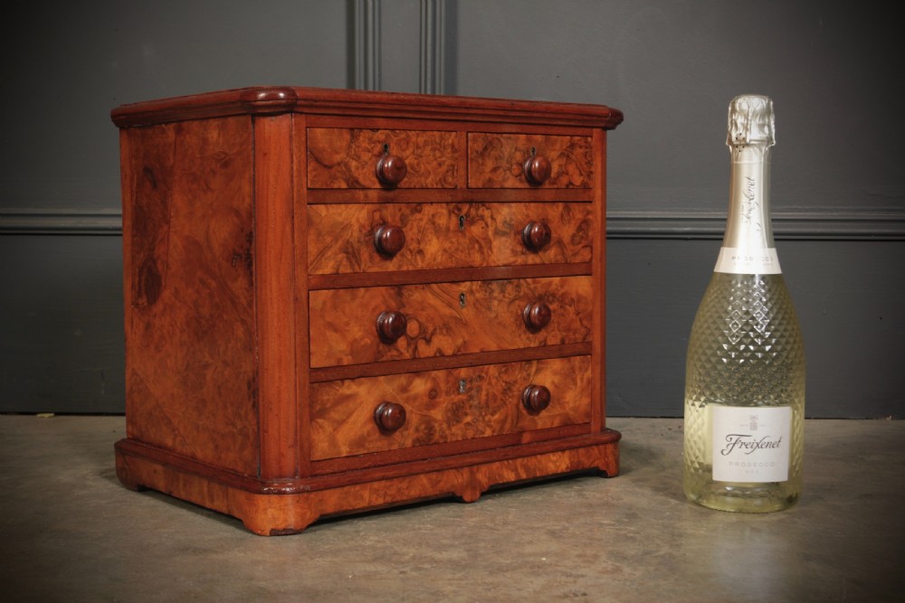 A miniature burr walnut chest of drawers featuring two short drawers above three long graduated drawers with turned wooden knob handles. View VII