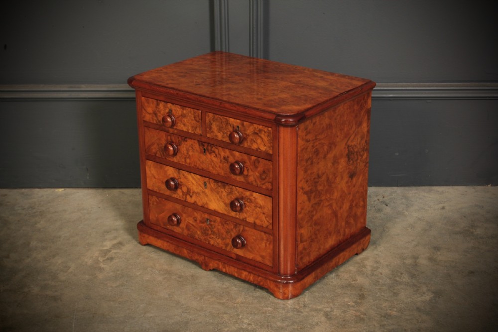 A miniature burr walnut chest of drawers featuring two short drawers above three long graduated drawers with turned wooden knob handles. View V