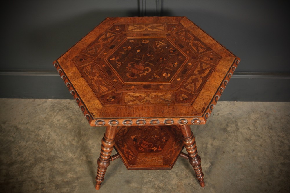 A Victorian hexagonal walnut occasional table featuring floral marquetry inlays, a carved edge, a lower tier, and turned legs. View VII