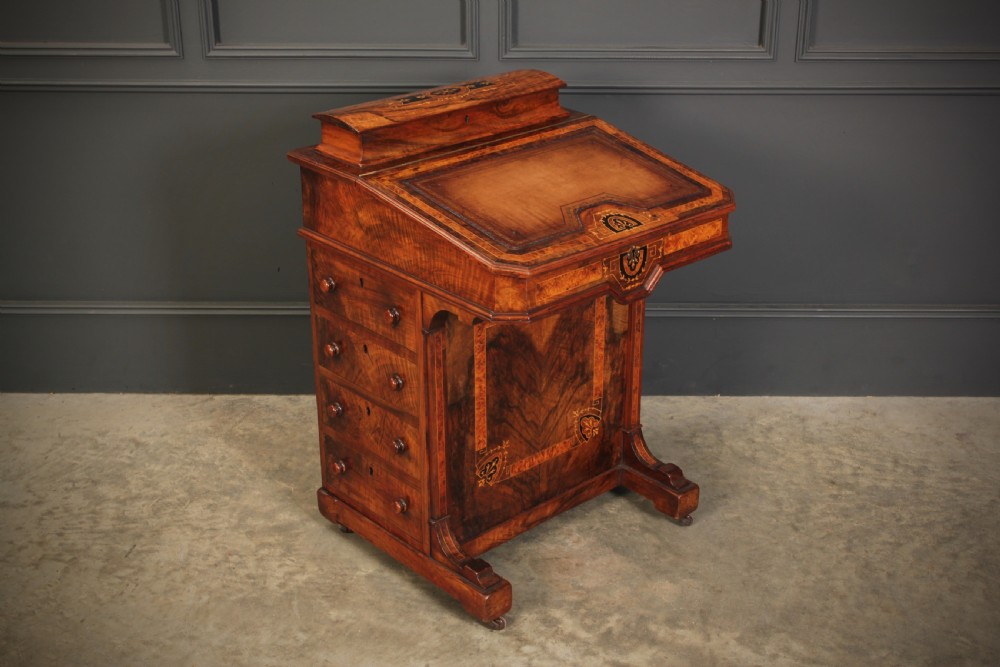 A Victorian figured walnut Davenport desk featuring a sloped leather writing top, intricate marquetry inlays, and a side bank of four drawers with turned wooden handles.