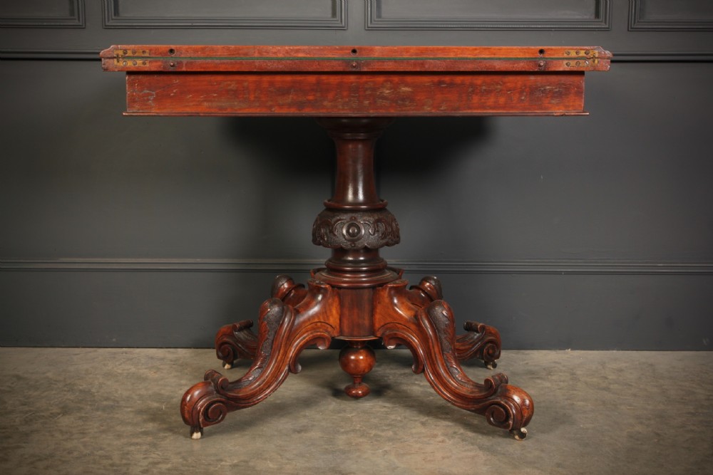 A Victorian figured walnut card table featuring floral marquetry inlay on a serpentine fold-over top, supported by a carved central stem and four cabriole legs on castors. View XIII