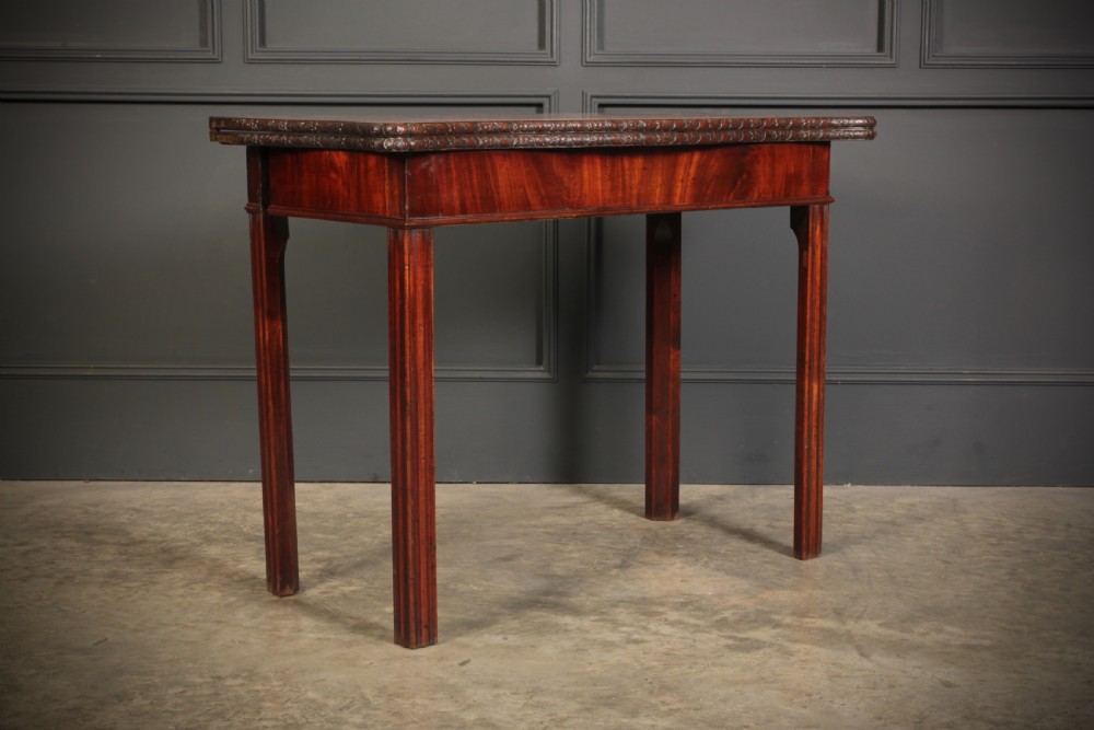 A George IV serpentine mahogany tea table featuring a fold-over top with carved edge moulding and straight fluted legs. View II