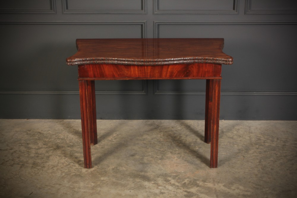 A George IV serpentine mahogany tea table featuring a fold-over top with carved edge moulding and straight fluted legs. View III