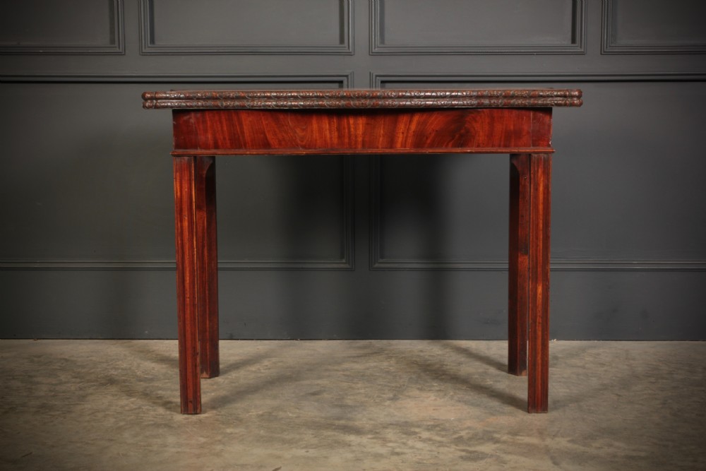 A George IV serpentine mahogany tea table featuring a fold-over top with carved edge moulding and straight fluted legs. View V