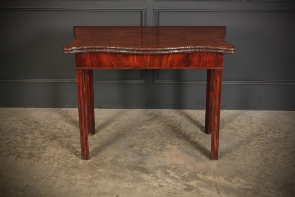 A George IV serpentine mahogany tea table featuring a fold-over top with carved edge moulding and straight fluted legs. View VI