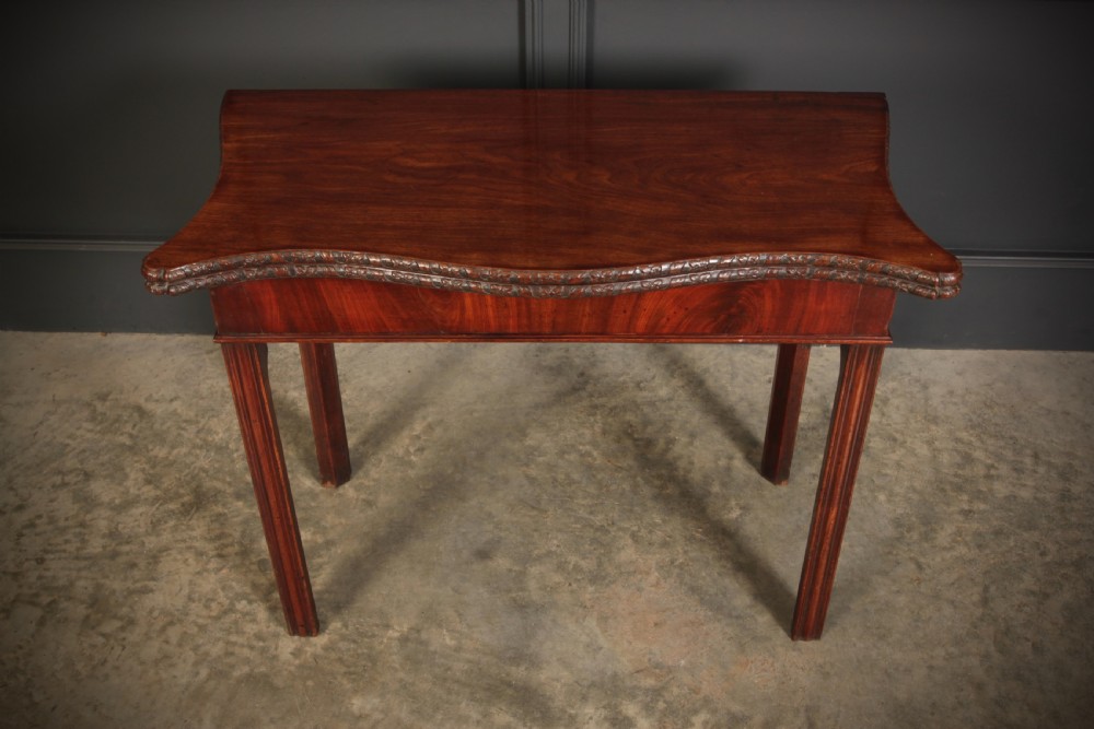 A George IV serpentine mahogany tea table featuring a fold-over top with carved edge moulding and straight fluted legs. View VII