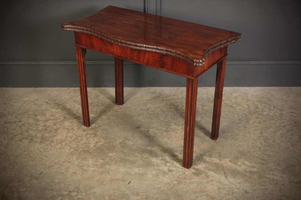 A George IV serpentine mahogany tea table featuring a fold-over top with carved edge moulding and straight fluted legs. View VIII