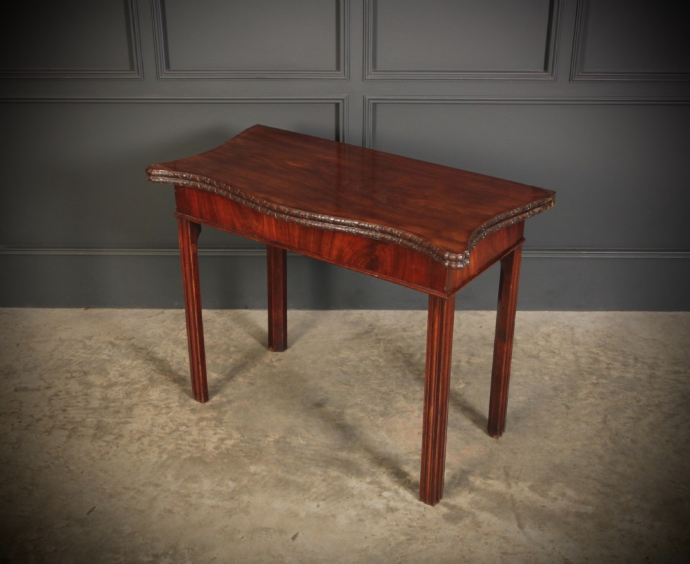 A George IV serpentine mahogany tea table featuring a fold-over top with carved edge moulding and straight fluted legs. View IX