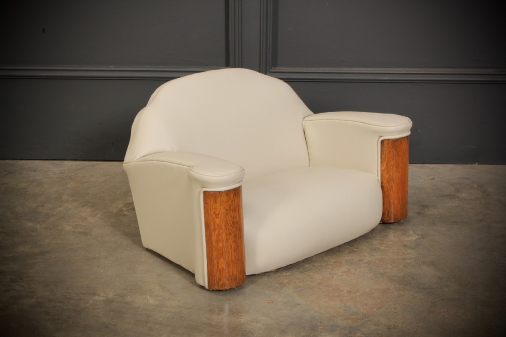 A miniature Art Deco three-piece suite featuring a small sofa and two matching armchairs upholstered in cream leather with polished curved wood arm fronts. View III