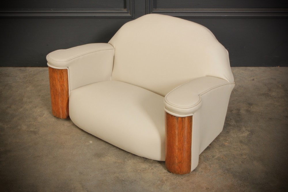 A miniature Art Deco three-piece suite featuring a small sofa and two matching armchairs upholstered in cream leather with polished curved wood arm fronts. View V
